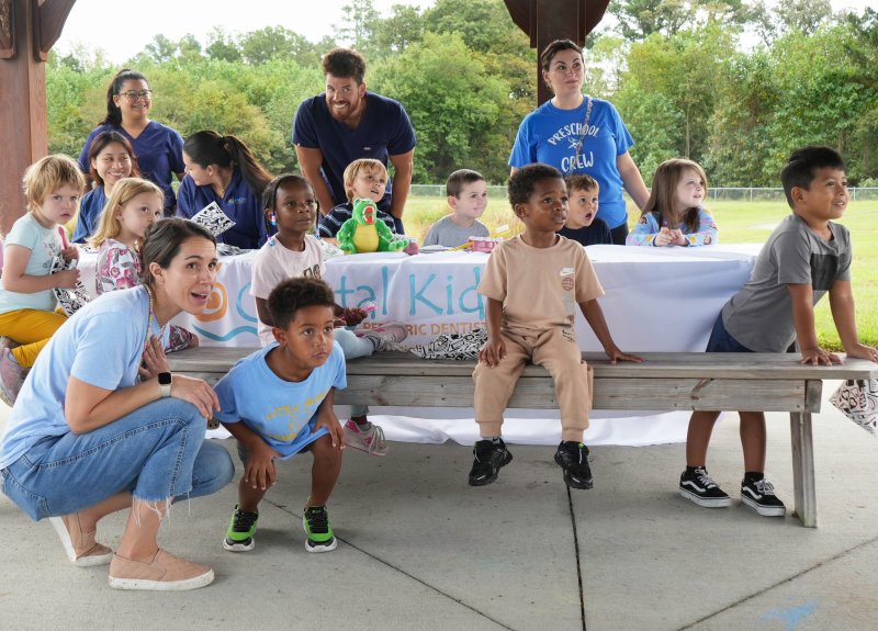 At the Coastal Kids Pediatric Dentistry station, kids and adults watch excitedly as the Delaware State Police helicopter takes off and leaves the event. Standing in back are (l-r) Yarenzi Navarro and Dr. Jeremy Irving of Coastal Kids Pediatric Dentistry and Little Vikings teacher Ashley Rowe. Sitting in back are (l-r) Coastal Kids’ Karina Niz and Karina Gonzalez, along with Little Vikings students Zayden Brown-Daniels, Emmett McCallum, Cameron Funhouser and Max Guidash. Sitting in front are Austin Johnson, Grace Harmansky, Danelda Davis-Tingle, Ji’Nier Wright and David Ramirez-Ortiz. Kneeling are paraeducator Liz Fortner and student Caden Kemmerlin.